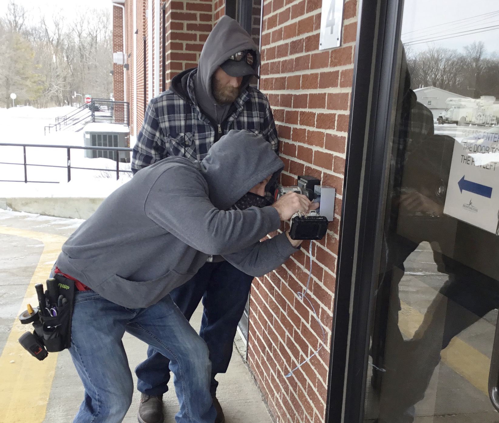 Stylus Technologies technicians installing an access-control reader at a commercial entrance